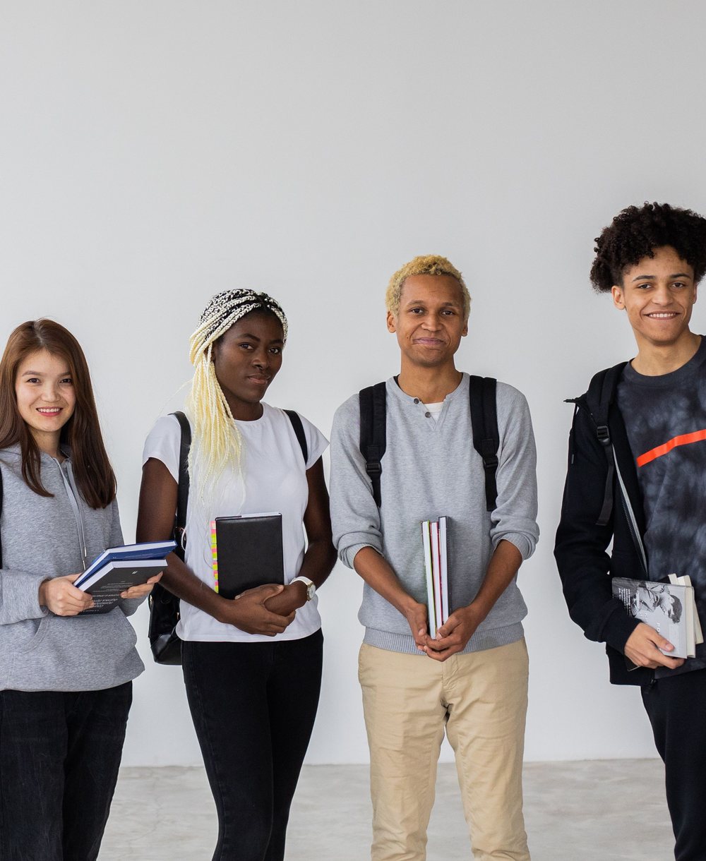 Four students of different backgrounds standing together with their books